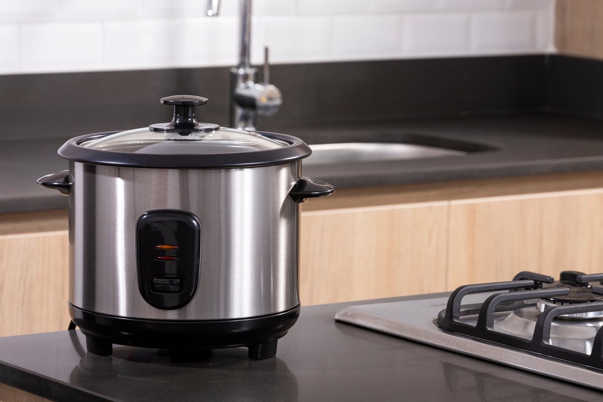 Small electric rice cooker on kitchen background